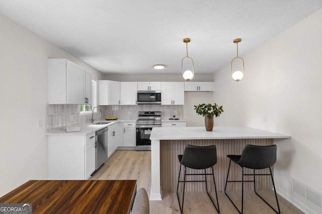 kitchen featuring tasteful backsplash, visible vents, appliances with stainless steel finishes, a peninsula, and a sink