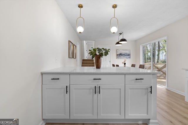 kitchen with light wood-style flooring, pendant lighting, white cabinetry, and a peninsula