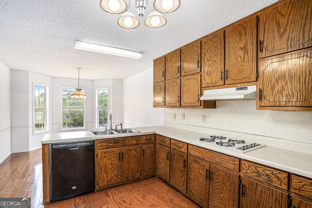 kitchen featuring an inviting chandelier, a sink, dishwasher, a textured ceiling, and under cabinet range hood