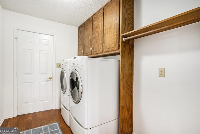 washroom featuring dark wood-type flooring, a textured ceiling, cabinet space, and washing machine and clothes dryer
