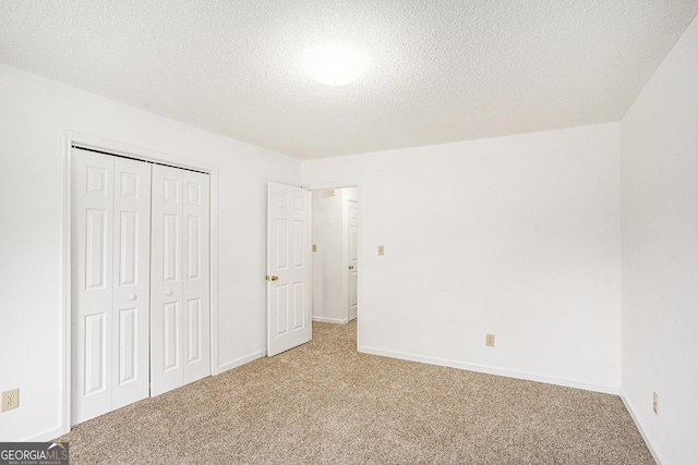 unfurnished bedroom featuring carpet floors, baseboards, a closet, and a textured ceiling