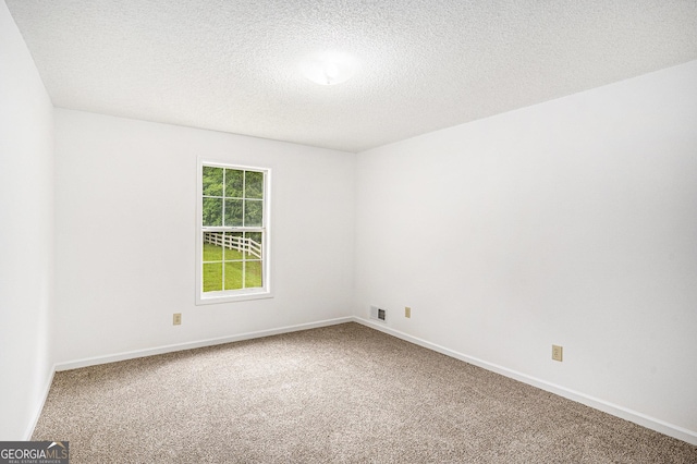 empty room featuring carpet floors, a textured ceiling, visible vents, and baseboards
