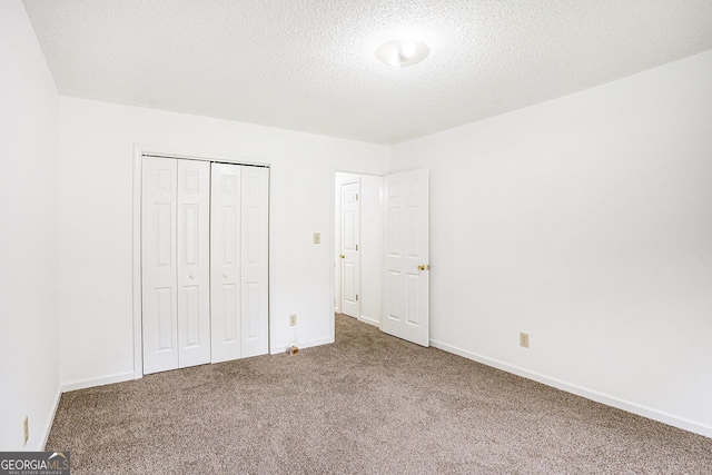 unfurnished bedroom featuring a closet, a textured ceiling, carpet, and baseboards