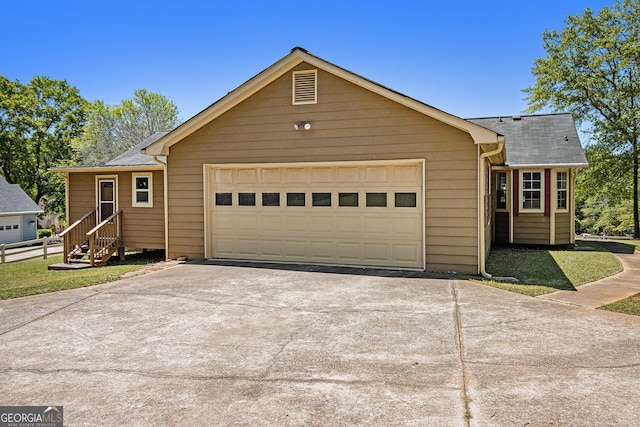 ranch-style home featuring concrete driveway, an attached garage, and roof with shingles