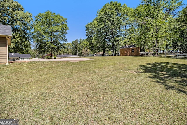 view of yard with fence, an outbuilding, and a shed