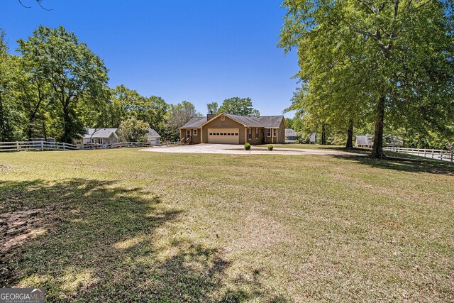 view of yard featuring a garage, fence, and driveway
