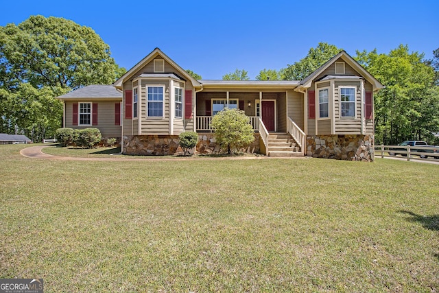 ranch-style house featuring fence, a porch, a front lawn, and stone siding