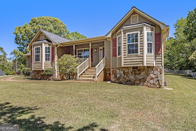 ranch-style home featuring covered porch, stone siding, fence, and a front yard
