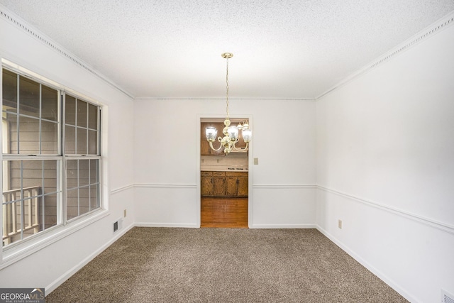 unfurnished dining area with carpet floors, ornamental molding, visible vents, a textured ceiling, and a notable chandelier