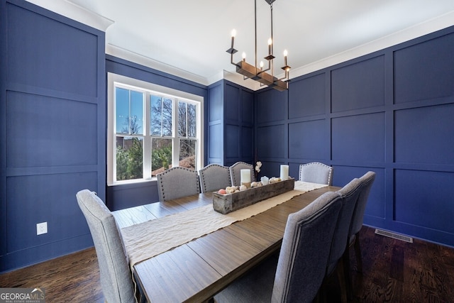 dining space featuring a decorative wall, a notable chandelier, dark wood finished floors, and visible vents