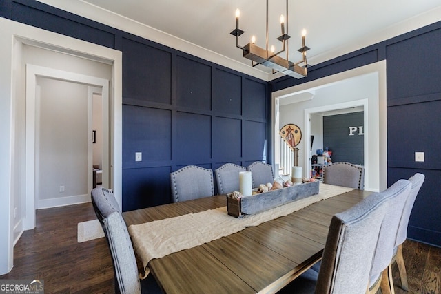 dining area featuring a decorative wall, baseboards, a notable chandelier, and dark wood finished floors