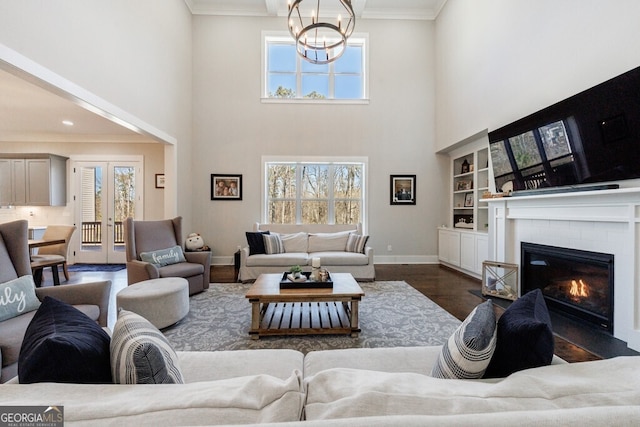living room featuring a notable chandelier, a high ceiling, crown molding, and wood finished floors