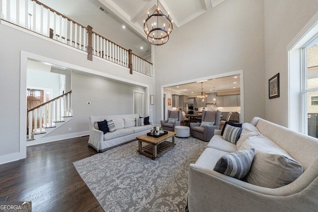 living room with baseboards, a chandelier, dark wood finished floors, stairway, and a towering ceiling