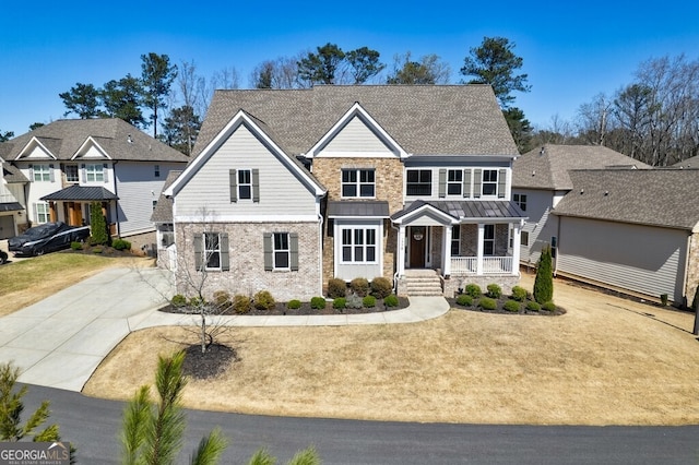 craftsman inspired home featuring stone siding, a front lawn, brick siding, a standing seam roof, and covered porch