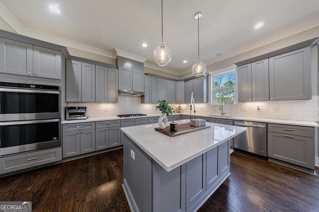 kitchen featuring a kitchen island, a sink, stainless steel appliances, gray cabinetry, and dark wood-style floors