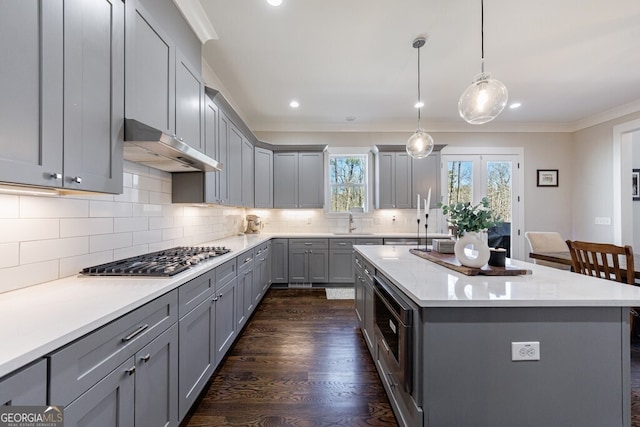 kitchen with light countertops, under cabinet range hood, gray cabinetry, and stainless steel appliances