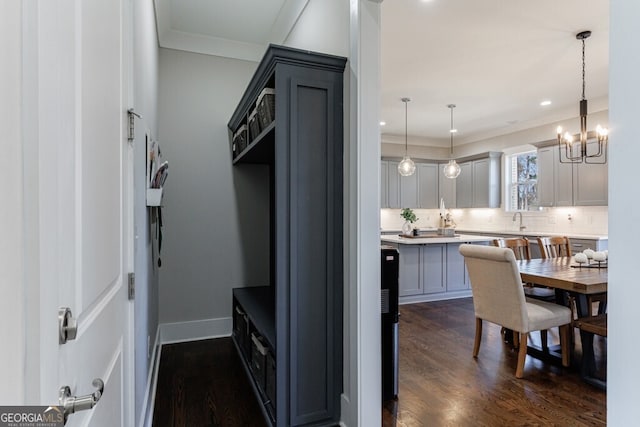 kitchen with tasteful backsplash, a notable chandelier, dark wood-style floors, crown molding, and gray cabinetry