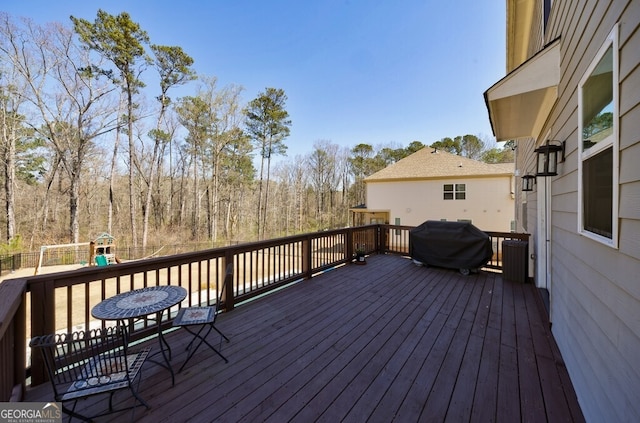 deck with a grill and a playground