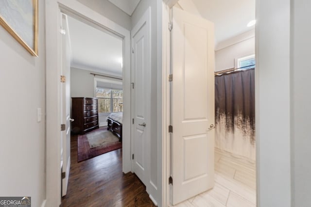 hall with wood finished floors and ornamental molding