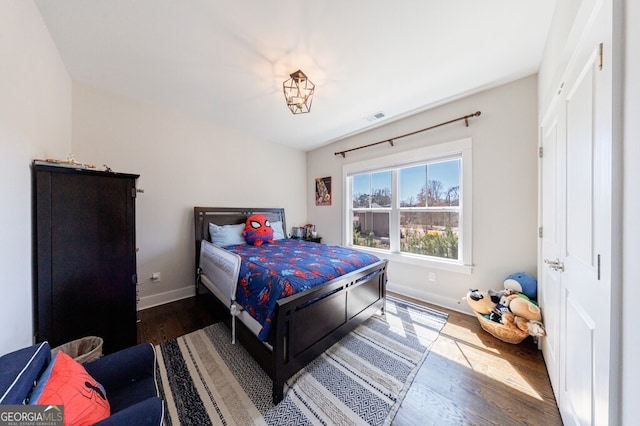 bedroom featuring visible vents, baseboards, and wood finished floors