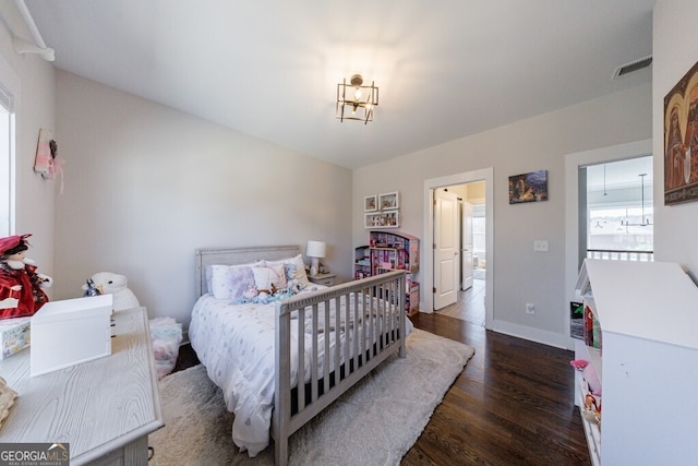 bedroom with visible vents, baseboards, and wood finished floors