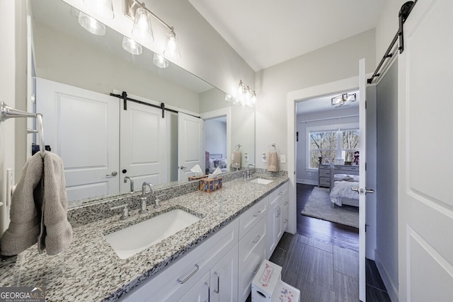 ensuite bathroom featuring double vanity, ensuite bathroom, a sink, and baseboards