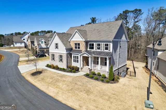 view of front of house with a standing seam roof, covered porch, stone siding, driveway, and central AC unit