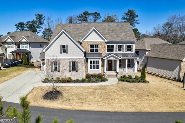 craftsman house with brick siding, a front yard, a porch, and a standing seam roof