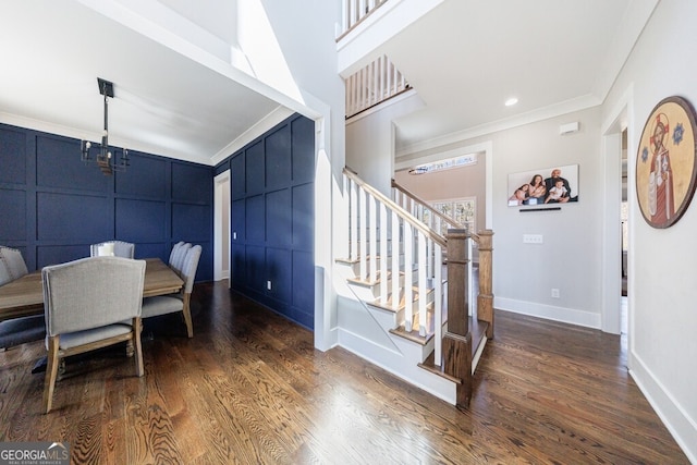 dining area featuring crown molding, a decorative wall, stairway, wood finished floors, and baseboards
