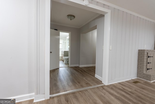 hall featuring wood finished floors, ornamental molding, and baseboards