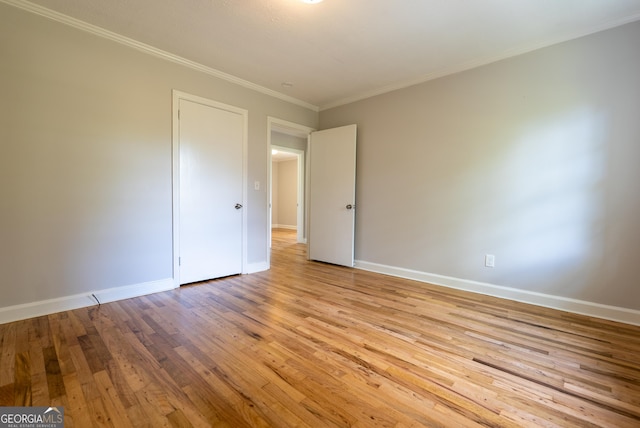 unfurnished bedroom featuring light wood-type flooring, baseboards, and crown molding