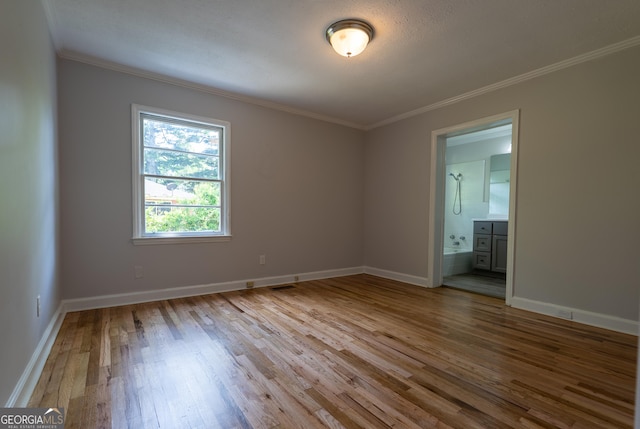 spare room featuring crown molding, wood finished floors, and baseboards