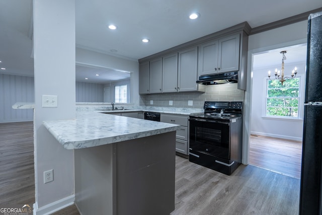 kitchen featuring black electric range, under cabinet range hood, a peninsula, gray cabinets, and a chandelier