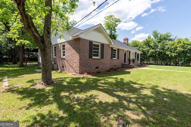 view of side of property featuring crawl space, brick siding, a chimney, and a yard