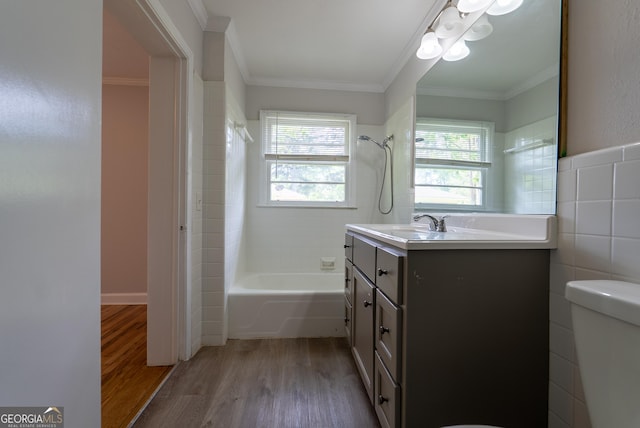 bathroom with wood finished floors, toilet, crown molding, vanity, and shower / bathtub combination