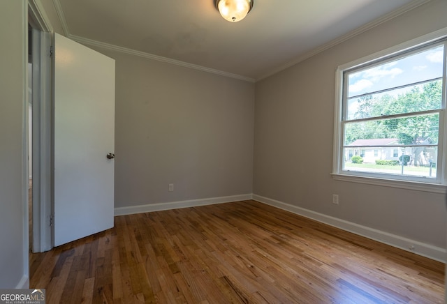 unfurnished room featuring hardwood / wood-style floors, baseboards, and crown molding