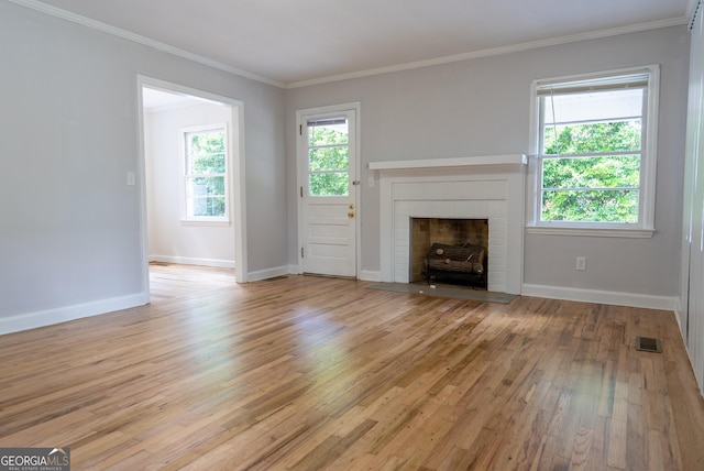 unfurnished living room with light wood-style floors, a brick fireplace, crown molding, and baseboards