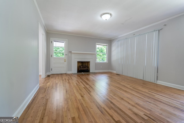 unfurnished living room featuring light wood finished floors, a fireplace, ornamental molding, and baseboards