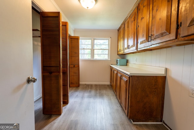 clothes washing area featuring light wood-style floors, crown molding, and baseboards