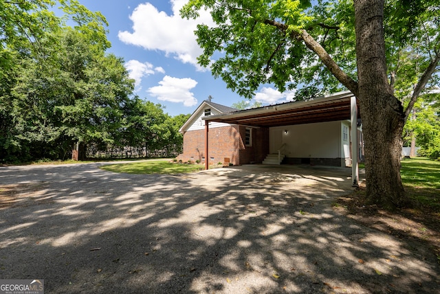 view of side of property featuring asphalt driveway, entry steps, and a carport