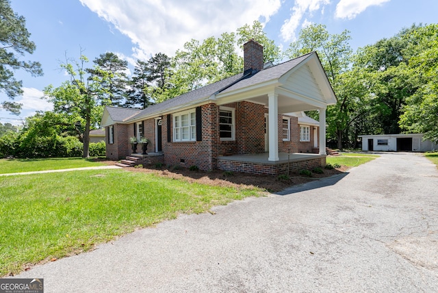 ranch-style house featuring a front lawn, brick siding, an outbuilding, a chimney, and a shingled roof