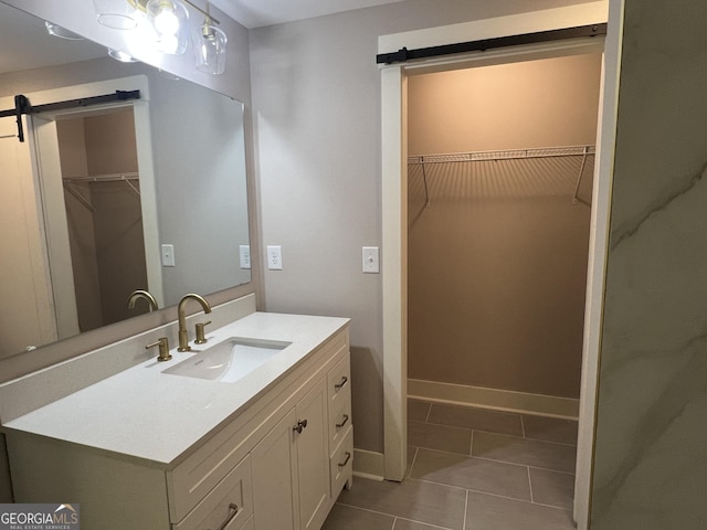bathroom with tile patterned floors, baseboards, vanity, and a walk in closet