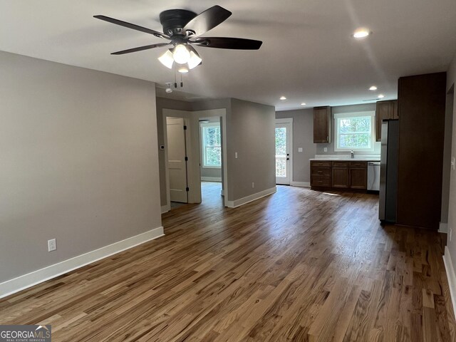 unfurnished living room featuring wood finished floors, a ceiling fan, and baseboards