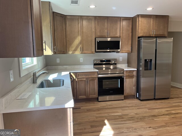 kitchen with light wood-style flooring, a sink, recessed lighting, and appliances with stainless steel finishes