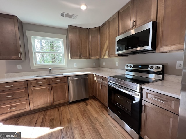 kitchen featuring a sink, light countertops, stainless steel appliances, light wood-style flooring, and visible vents