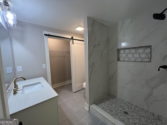 full bathroom with a marble finish shower, a spacious closet, vanity, and toilet