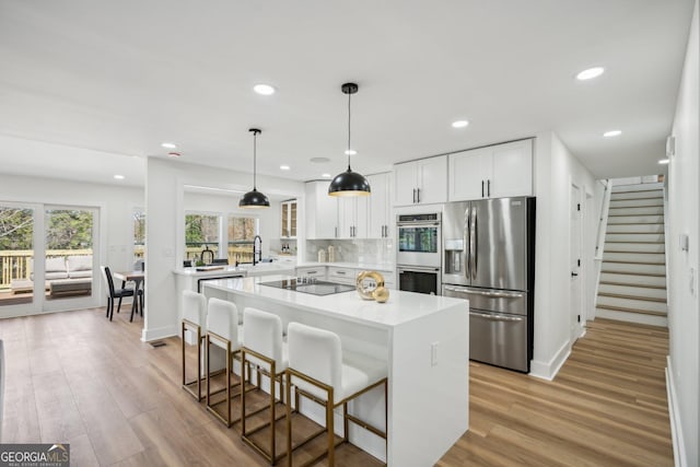 7410 Fields Dr, Cumming, GA 30041 - kitchen with tasteful backsplash, white cabinetry, appliances with stainless steel finishes, a breakfast bar area, and light countertops