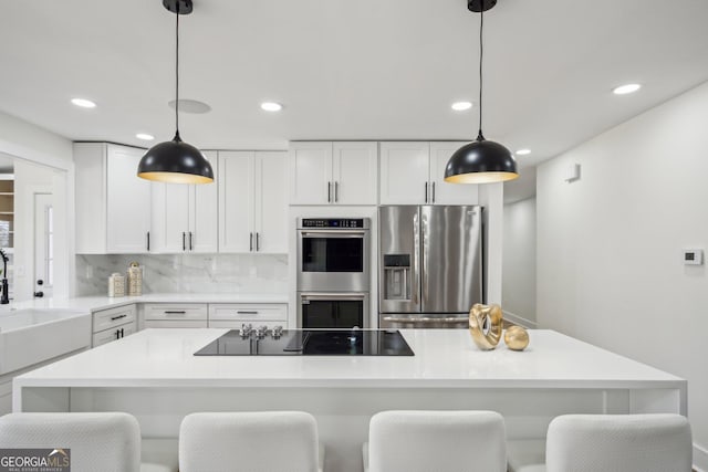 7410 Fields Dr, Cumming, GA 30041 - kitchen featuring light countertops, decorative backsplash, appliances with stainless steel finishes, white cabinets, and a sink