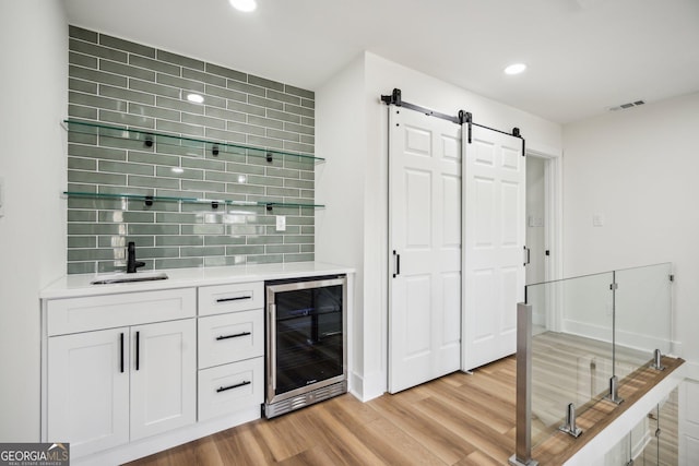 7410 Fields Dr, Cumming, GA 30041 - bar with wet bar, a sink, wine cooler, light wood-style floors, and a barn door