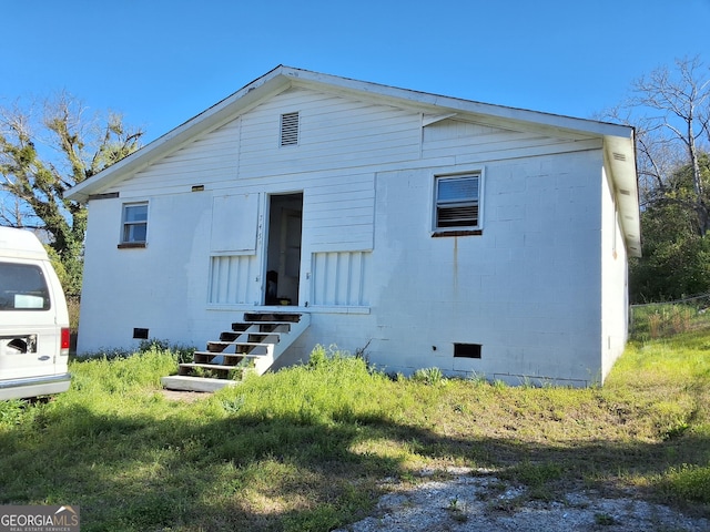 rear view of house featuring concrete block siding, crawl space, and entry steps